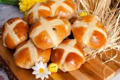 Hot Cross Buns on a wooden board with daffodils and toy chicks around them