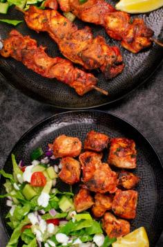 Tandoori Chicken Tikka Kebab skewers on a black plate and cubes of tikka chicken served with a side salad on another black plate